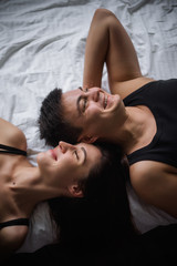 Top view of couple in love. Close-up portrait of the Lovers who lie on the bed at home, head to head. The morning of the newlyweds, tenderly resting on festive day off at home. Concept of tactility