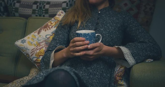 Young woman sitting on sofa with a cup of coffee