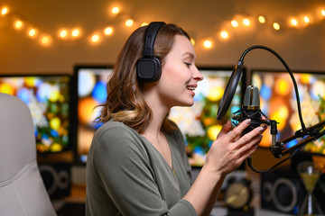 A girl radio host in a cozy atmosphere broadcasts with a studio microphone. Stream, live broadcast,...