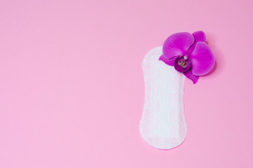 daily hygienic, sanitary pad with a flower orchid on pink background. hygiene, care and cleanliness of woman. copy space