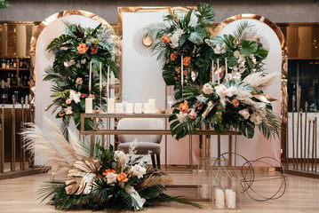 Wedding luxury decor. Wedding presidium for the newlyweds. Beautiful decor with pastel roses, candles and greenery. Indoors