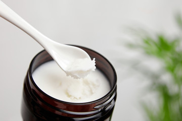 Shea butter in jar with spoon, cosmetic product for moisturizing skin.