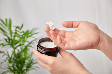 Shea butter in jar, cosmetic product for moisturizing skin. Female hand holds container with white anti-aging smoothing and soothing cream