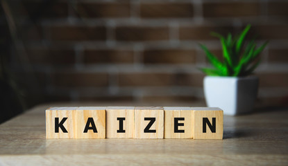 Kaizen improvement sign made of blocks on a wooden desk in a bright room