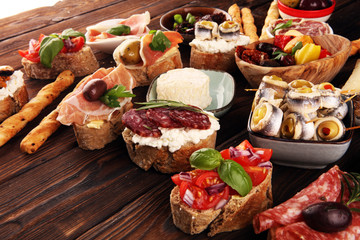 Appetizers table with italian antipasti snacks and wine in glasses. Brushetta or authentic traditional spanish tapas set, cheese variety
