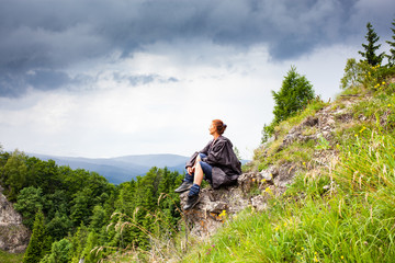 woman hiker with raincoat looking at beautiful spring landscape