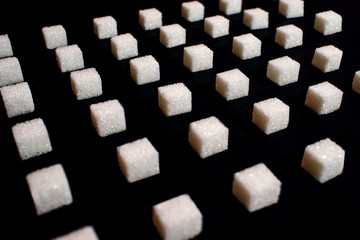 background from sugar cubes on a black background, white sugar create a uniform pattern on a black background