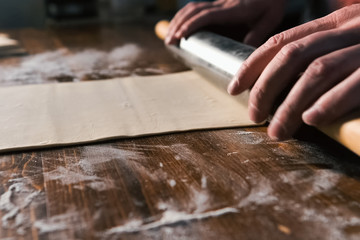 rolling out the dough with rolling pin on the table.