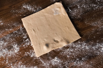 rolling out the dough with rolling pin on the table.