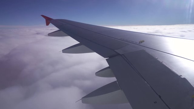 Wing of an airplane flying above the sky with clouds