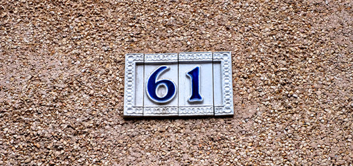 Number 61, sixty-one, ornamental tiles with blue digits on light brown background.