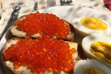 Sandwich with red caviar and boiled eggs, coffee mug. Morning br