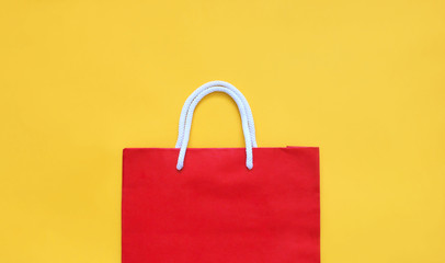 Red shopping paper bag on the yellow background with copy space. Summer sale concept.