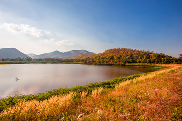 The blurred panoramic nature background of sunlight hitting the lake's surface, grass and wind blowing all the time along the large mountains, ecological beauty and fresh air.