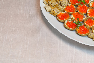 Sandwiches with red caviar on white plate close up