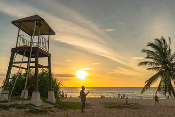 a man walking and take photo around lifegaurd tower during sunset at Karon beach Phuket