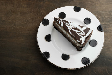 swirly chocolate cheese cake on a white plate with black polka dots on a wooden table top