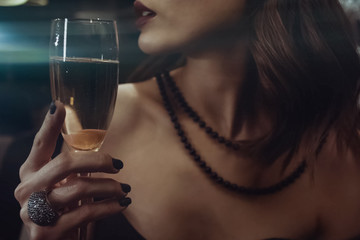 woman holds glass of champagne near lips. © Ludmila