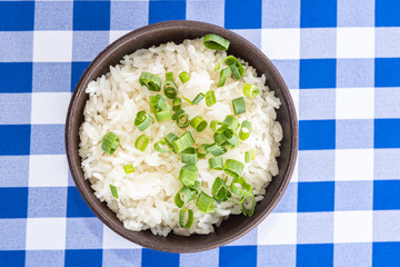 Bowl of white rice with green onion on the table - typical brazilian food