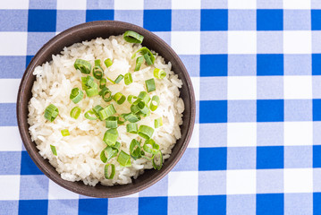 Bowl of white rice with green onion on the table - typical brazilian food