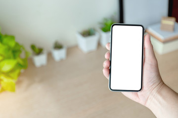 Mockup image blank white screen cell phone.man hand holding texting using mobile on desk at office.background empty space for advertise text.people contact marketing business,technology 