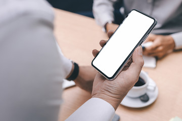 Mockup image blank white screen cell phone.man hand holding texting using mobile on desk at office.background empty space for advertise text.people contact marketing business,technology 