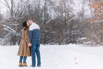 Fototapeta na wymiar Love Valentine Concept. people, season, love and leisure concept - happy couple hugging and kissing outdoors in winter. Romantic couple in love feeling happiness romance Valentine . love copy space.