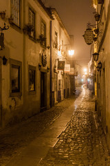Fototapeta na wymiar OBIDOS, PORTUGAL - OCTOBER 11, 2017: Night view of a narrow cobbled street in Obidos village, Portugal