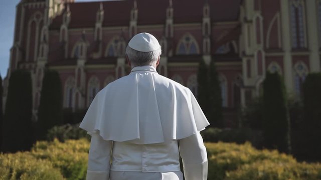 Religion: pope walks through the Vatican garden at sunset. Slow motion