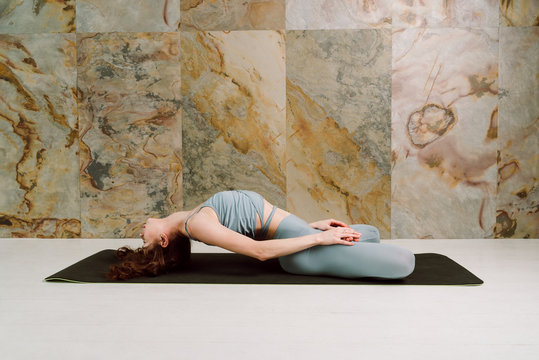 Young yogini practicing Matsyasana pose in pastel blue leggins and top, selective focus