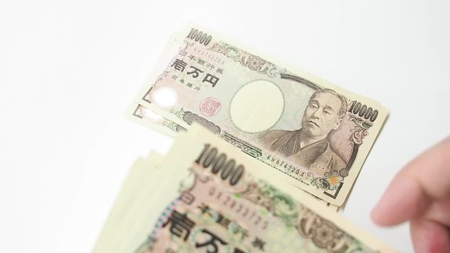 Hand counted Japanese Banknote money on white table. Concept for japan economic and financial business.
