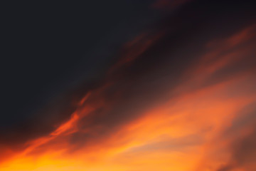 Dramatic atmosphere blurry image of twilight sky and golden cloud look like fire flame on dark sky background.