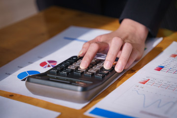 Businesswoman working on calculator to calculate business data financial report on wooden table. Business financial analysis and strategy concept.