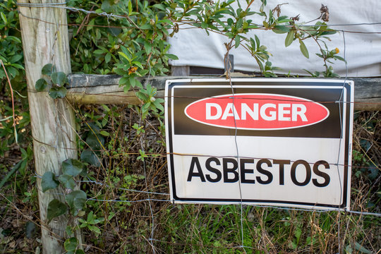 A warning sign Danger Asbestos on a fence at site rehabilitated post asbestos contamination