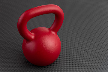 Simple fitness, red kettlebell on a black gym floor
