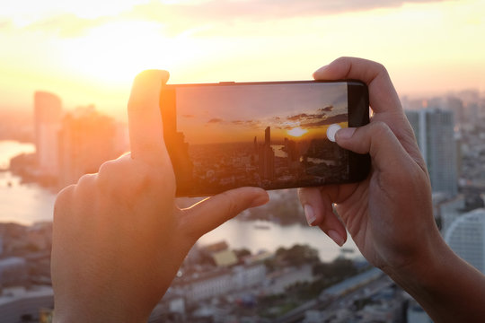 Soft focus .Young people take pictures of the buildings in the city. Sunrise time He uses a high-angle recording photo phone.Travel concepts and technology