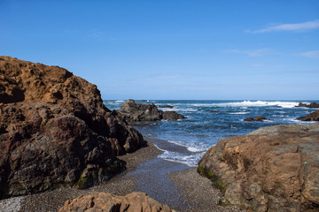 California coast with big rocks and waves coming up on the sandy shore