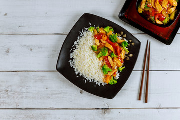 Rice with stir fry chicken and vegetable on black square plate. Chinese cuisine.