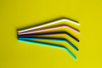 5 multi-colored silicon straws on yellow background