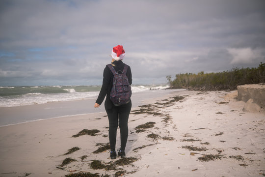 A girl wears a Santa hat as she walks down the beach in Florida