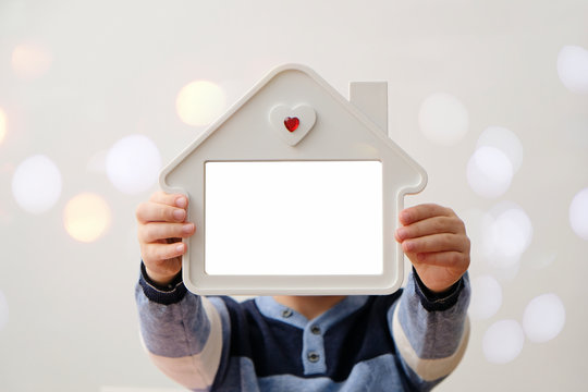 Child holding photo frame house shaped. Cozy comfort love home concept