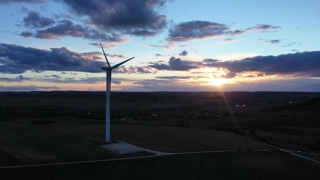 Une &eacute;olienne au milieu des champs au cr&eacute;puscule	au coucher du Soleil