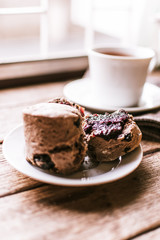 Sliced dried fruit chocolate scones with jam in the small saucer. 