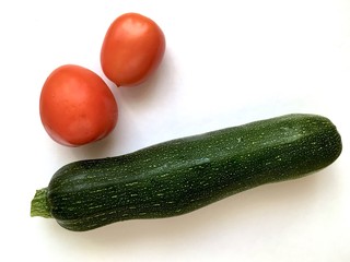 Zucchini and tomato on a white background. Harvest flat lay
