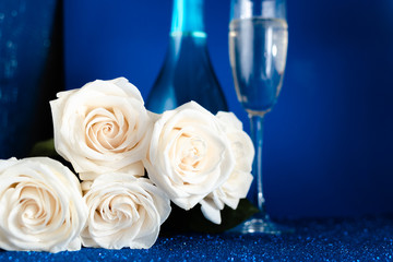 Two glasses of cold champagne and a bouquet of white roses on classic blue  background. Saint Valentine's and women's day  concept.
