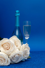 Two glasses of cold champagne and a bouquet of white roses on classic blue  background. Saint Valentine's and women's day  concept.