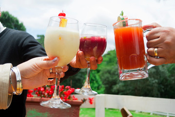 Man and woman hands making toast with alcoholic drinks outdoors, drinks prepared by bar tender in Guatemala.