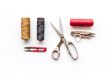 Sewing concept. Thread and sciccors on white background top-down pattern