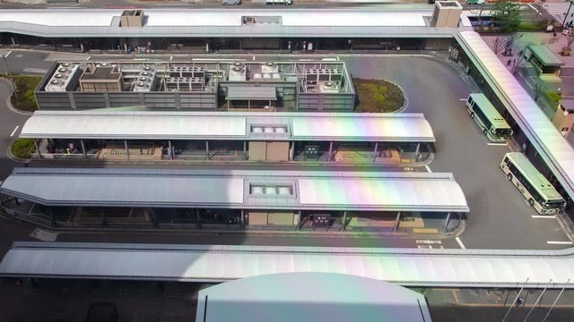 Timelapse Kyoto intercity and commuter bus station terminal with passengers waiting on roofed platforms and coaches on sunny day