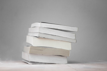 A stack of old books resting on a dusty desk in room.